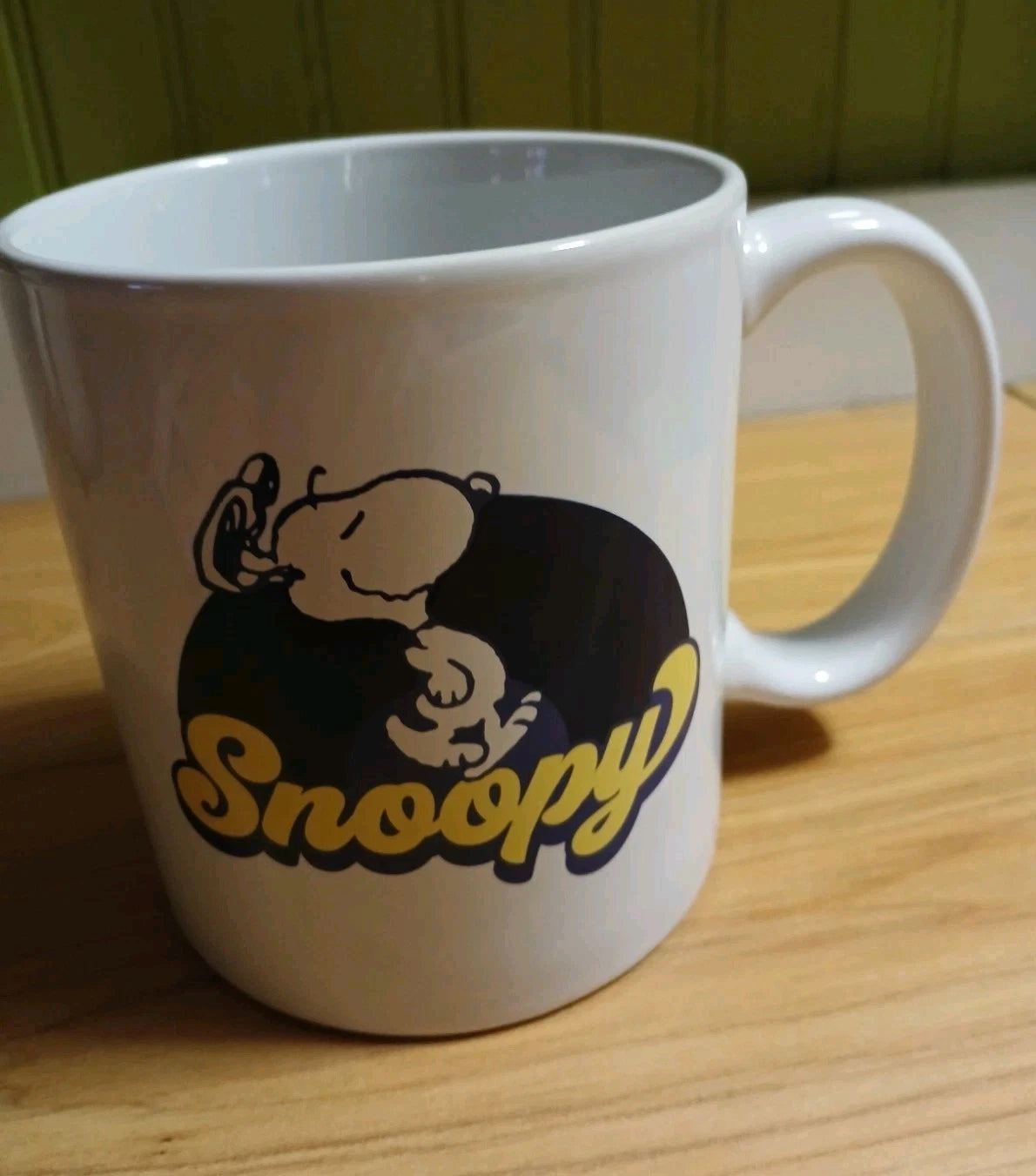 White mug with Snoopy design on a wooden surface